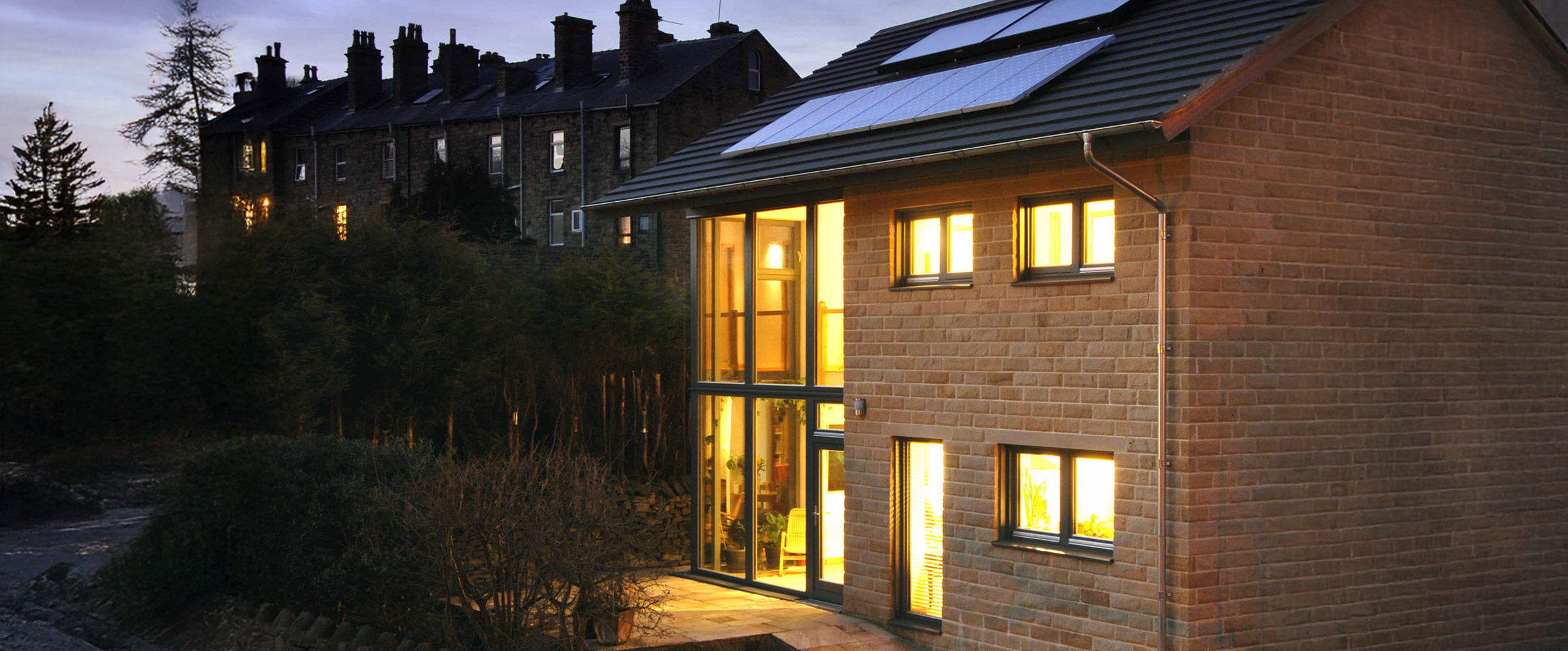 Low-energy home with solar panels illuminated at dusk